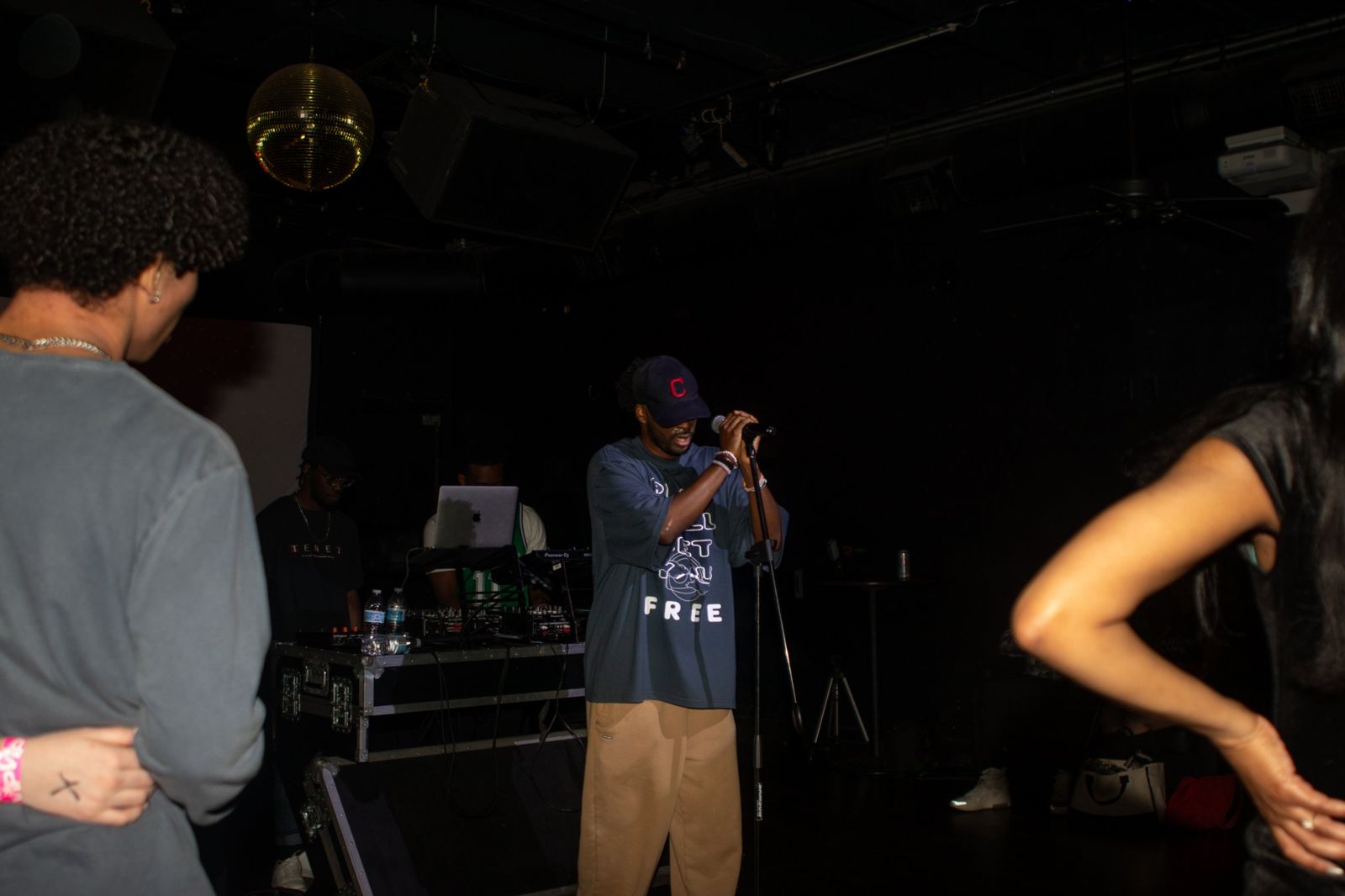 Ryan singing into a mic in a dark club, DJs behind him and fans in the foreground